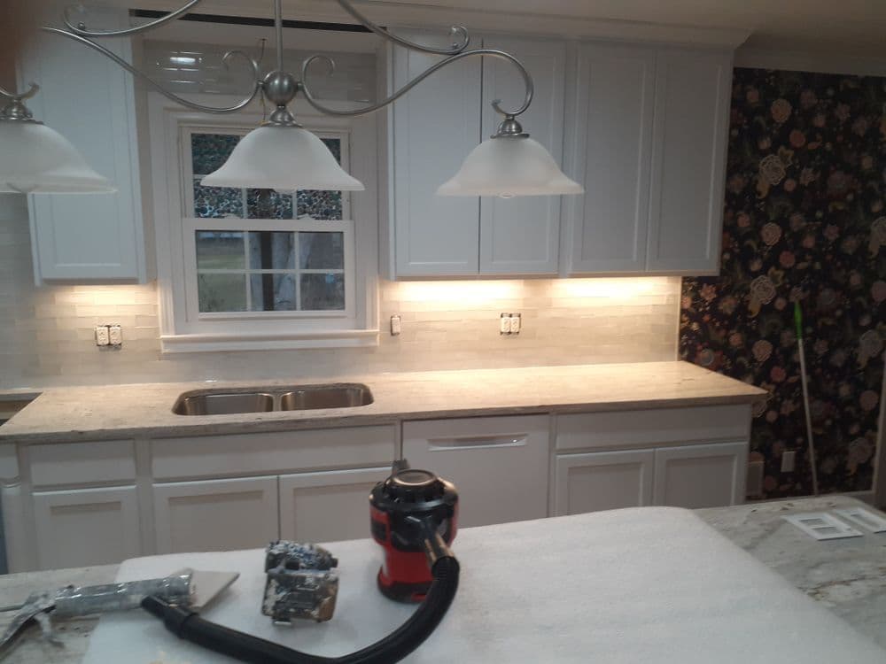 Modern kitchen with white cabinets, granite countertop, and floral wallpaper accents.