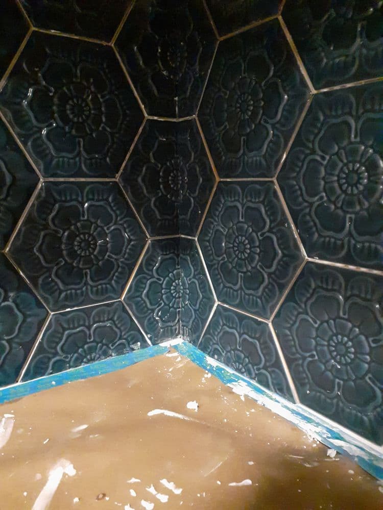 Dark green hexagonal tiles with floral pattern in a corner, freshly installed.