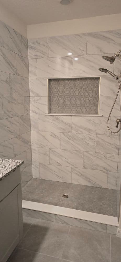 Modern bathroom shower with marble tiles, hexagon niche, and sleek floor design.