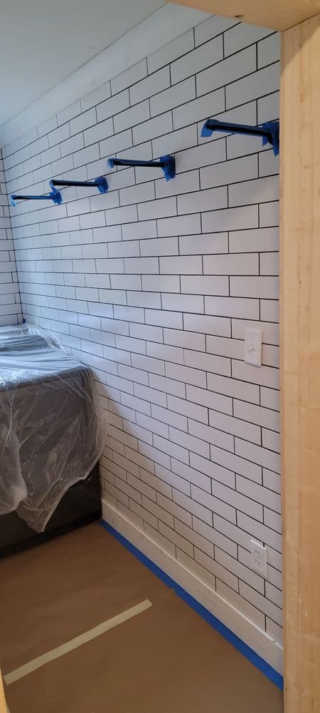 Modern kitchen under renovation with white subway tile and blue painter's tape.