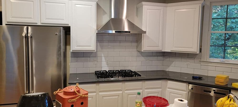 Modern kitchen with white cabinets, stainless steel appliances, and a gas stove backsplash.