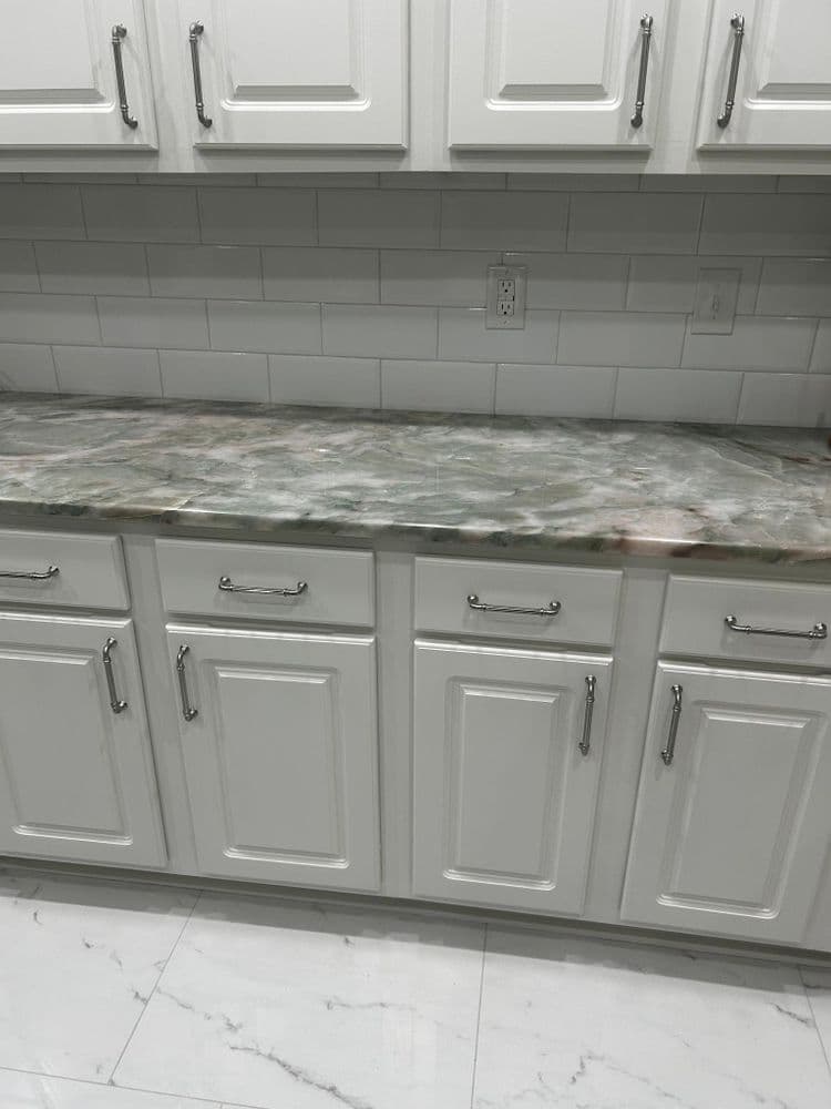 Modern kitchen with white cabinets, marble countertop, and white tiled backsplash.