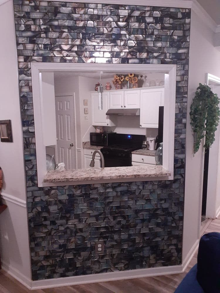 Modern kitchen pass-through with stylish stone backsplash and granite countertop design.