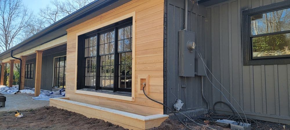 Newly constructed window trim on a modern home with wooden and gray siding.