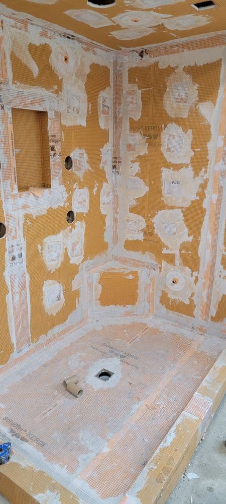 Unfinished shower renovation with waterproof membrane and tile backer installation.
