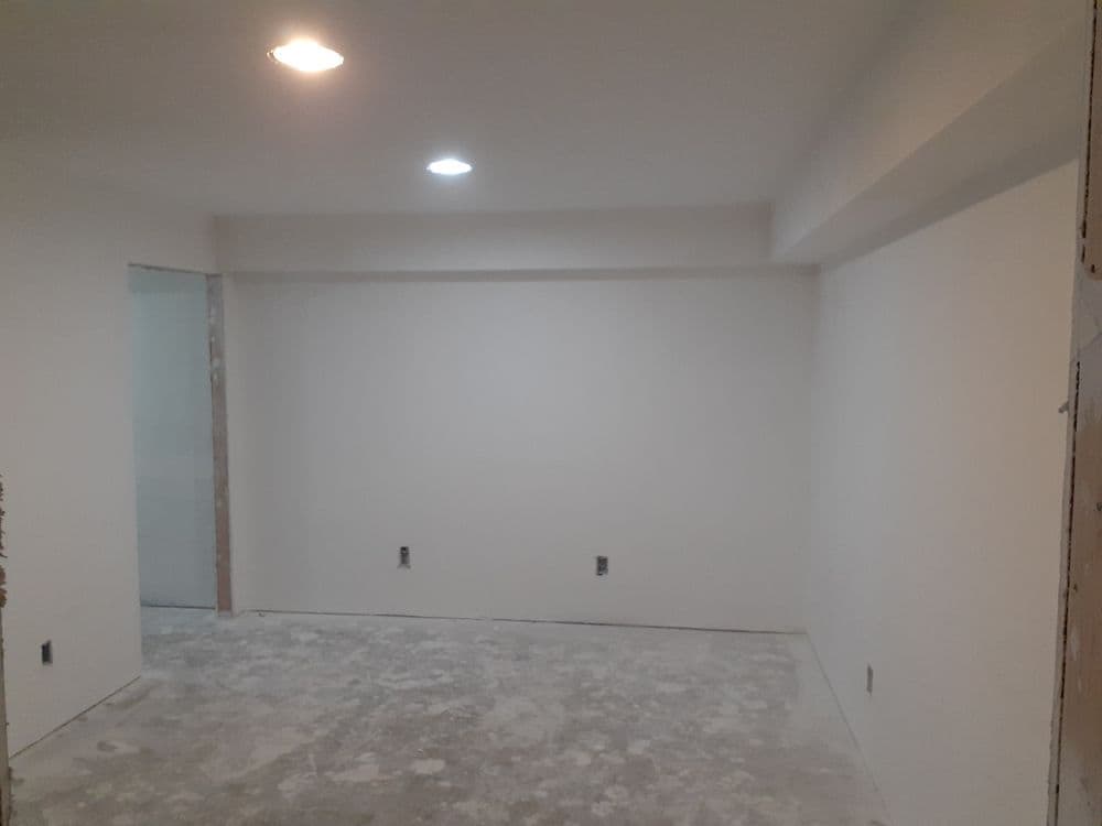 Empty room with unfinished drywall, overhead lighting, and a concrete floor.