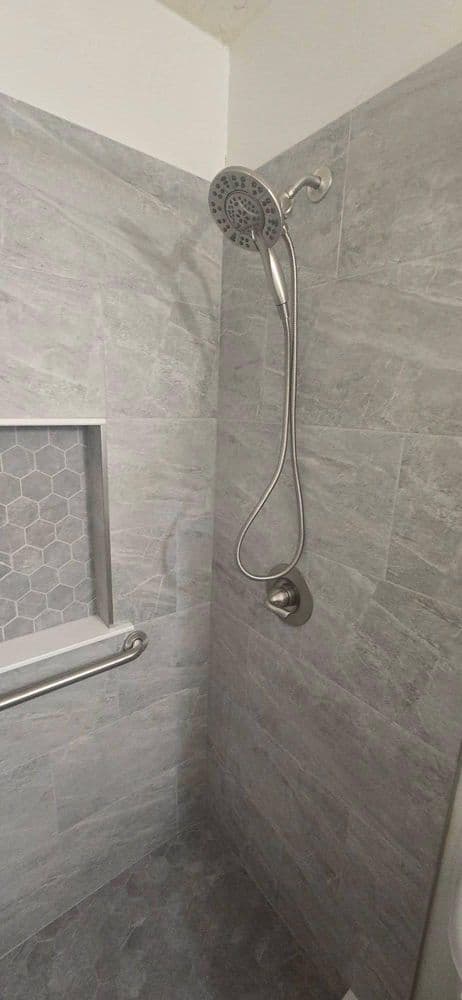 Modern shower with hexagon tile, stainless steel showerhead, and sleek grab bar.