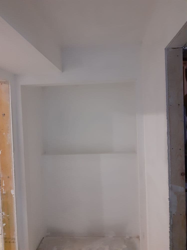 Empty room with white walls and a built-in shelf, showcasing an unfinished space.