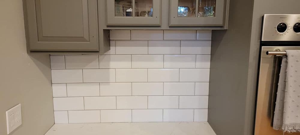 Modern kitchen backsplash featuring classic white subway tiles and gray cabinetry.