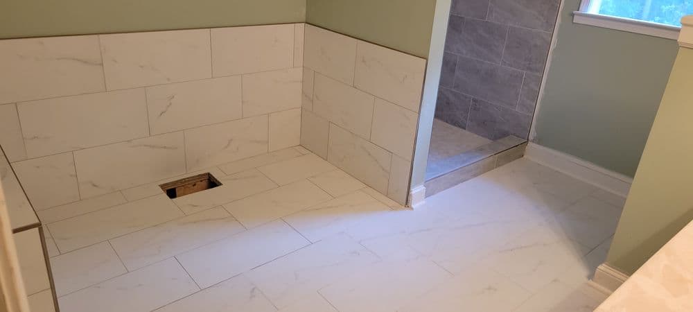 Newly installed bathroom with white marble tile flooring and light green walls. Shower area visible.