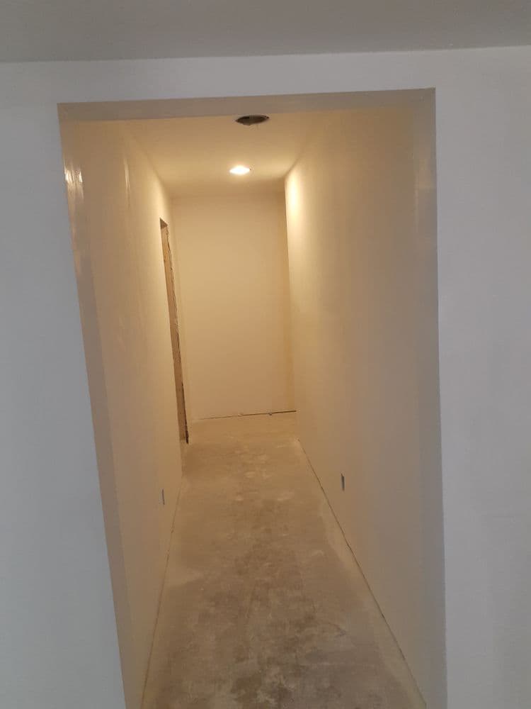 Empty interior hallway with smooth white walls and overhead lighting.