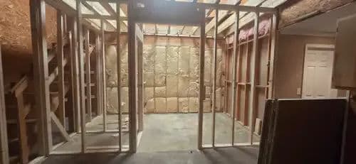 Interior of a framed room under construction with insulation visible on the walls.