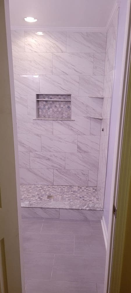 Modern bathroom shower featuring marble tiles and mosaic accent details.