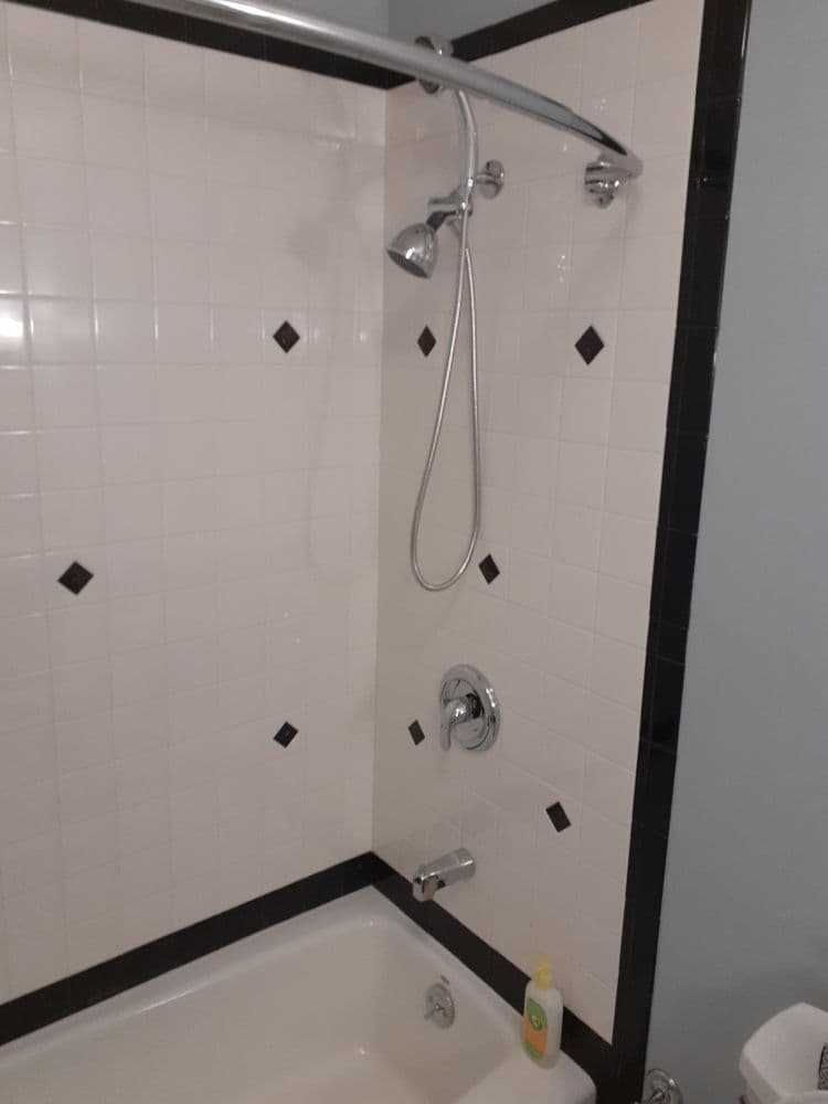 Modern bathroom shower with chrome fixtures, white tiles, and a bathtub. Ideal for home improvement.