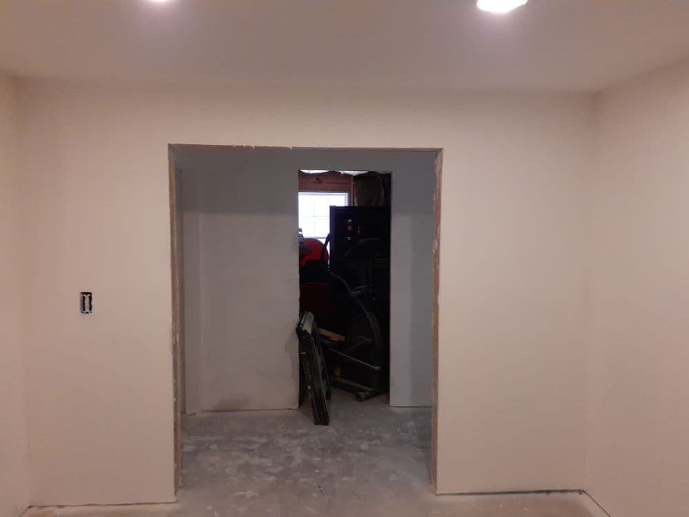 Interior view of a room with an unfinished wall opening, natural light illuminating the space.