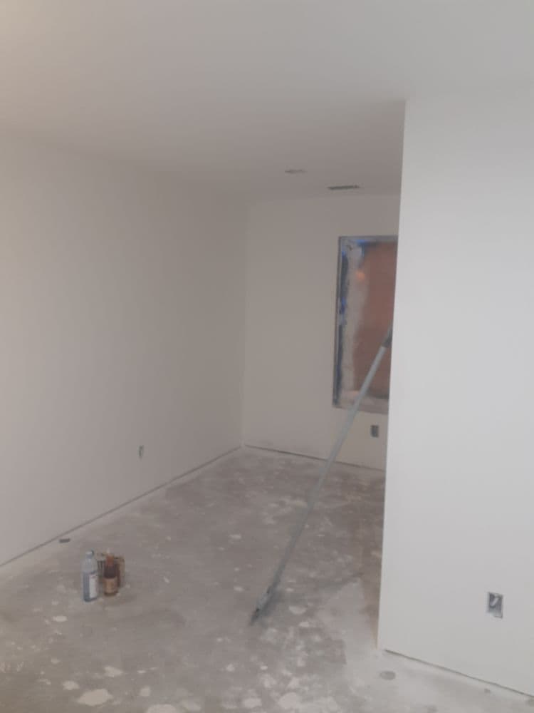 Empty room with freshly painted white walls and construction tools on the floor.