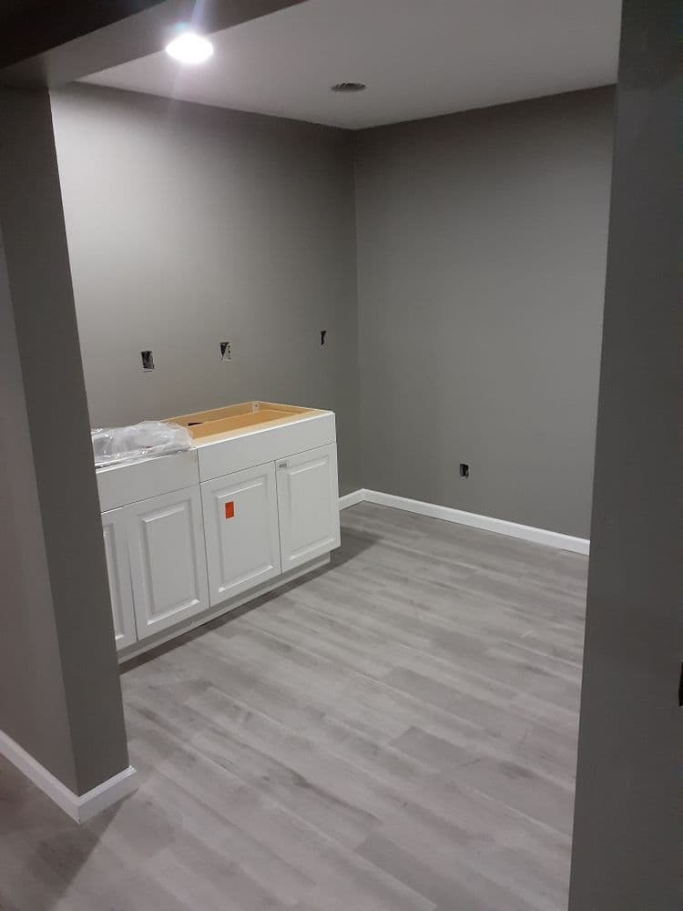 Empty room featuring gray walls, white cabinetry, and light hardwood flooring.