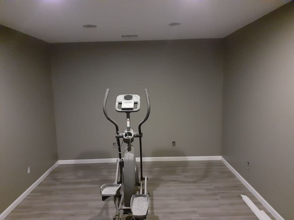 Home gym with elliptical machine in spacious, neutral-toned room.
