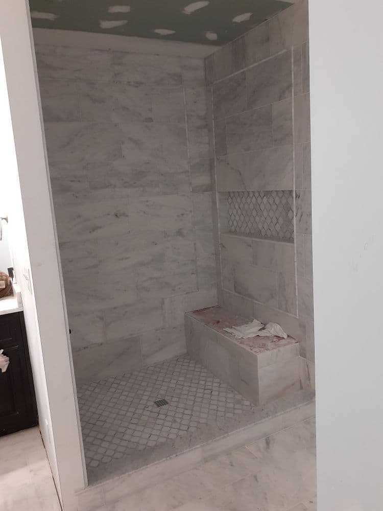 Modern marble shower renovation featuring a built-in bench and stylish tile design.