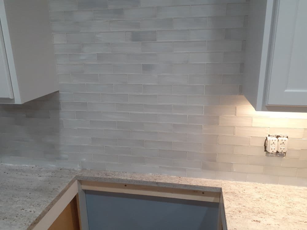 Modern kitchen backsplash with light grey subway tiles and under-cabinet lighting.