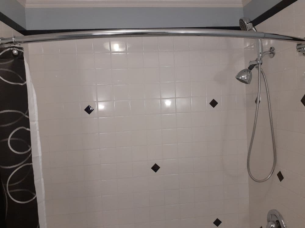 Shower with chrome fixtures, tiled walls, and decorative black diamond accents.
