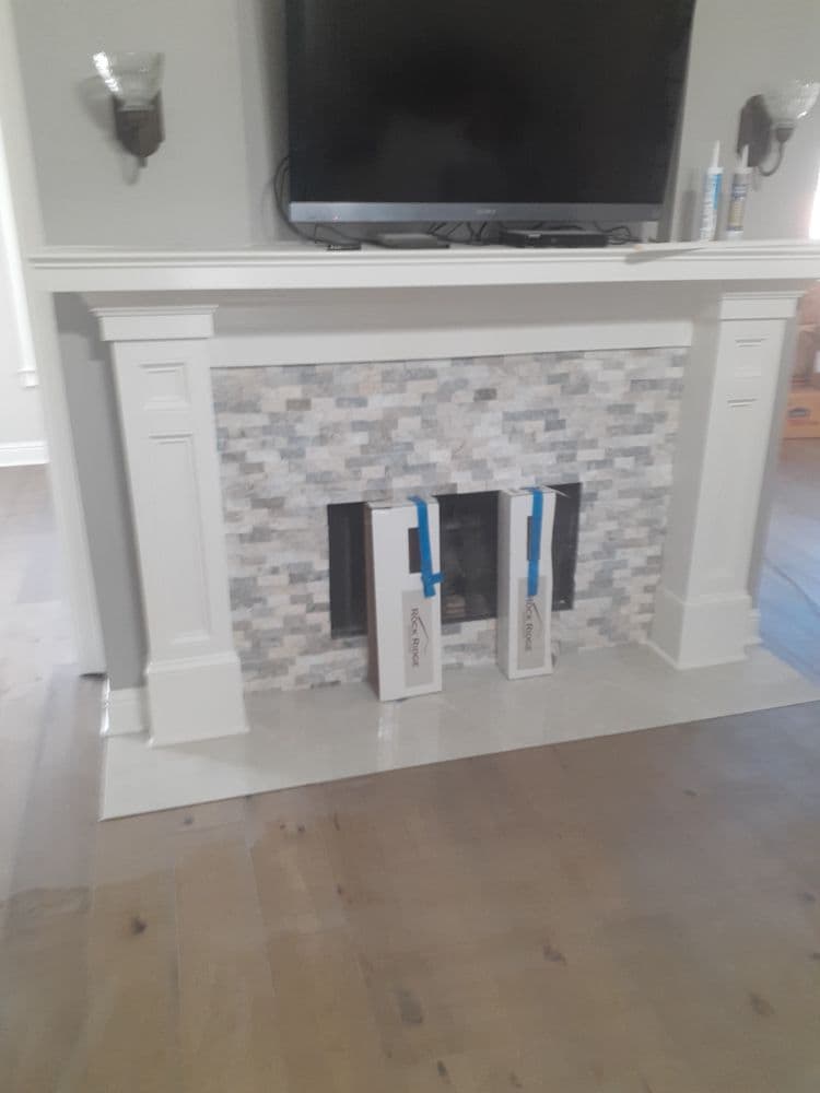 Modern home interior featuring a stylish fireplace with mosaic tile and two decorative boxes.