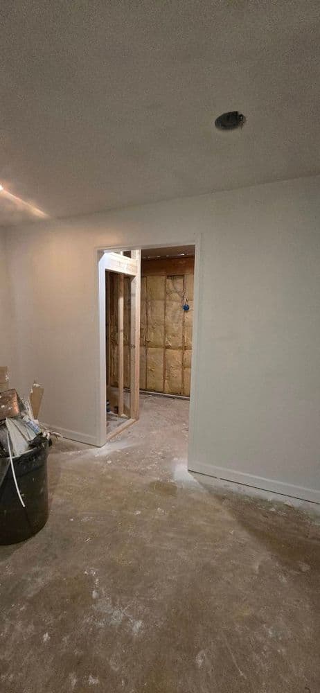 Renovated interior space showing an open doorway and construction materials on the floor.