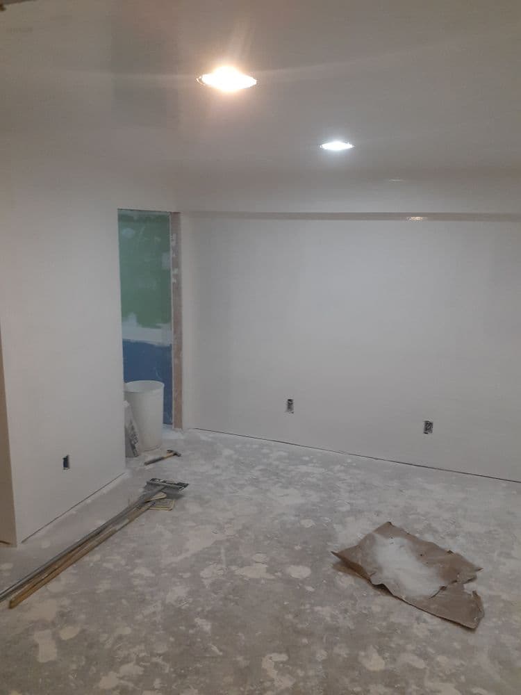 Home renovation progress: freshly painted room with construction materials and lighting visible.