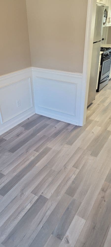 Modern kitchen featuring light gray laminate flooring and elegant wainscoting details.