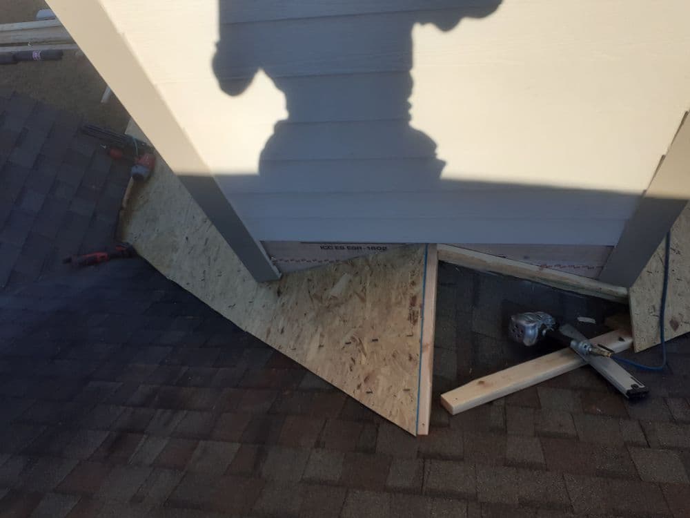 Construction area showing roof shingles, plywood, and tools for home improvement project.