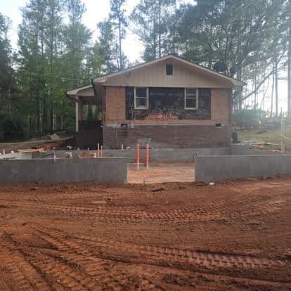 Renovation of a house with a new foundation and surrounding dirt landscape.