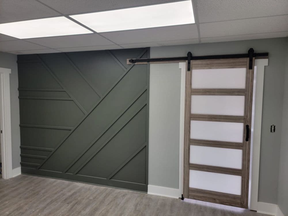 Modern interior design featuring a green accent wall and a sliding barn door.