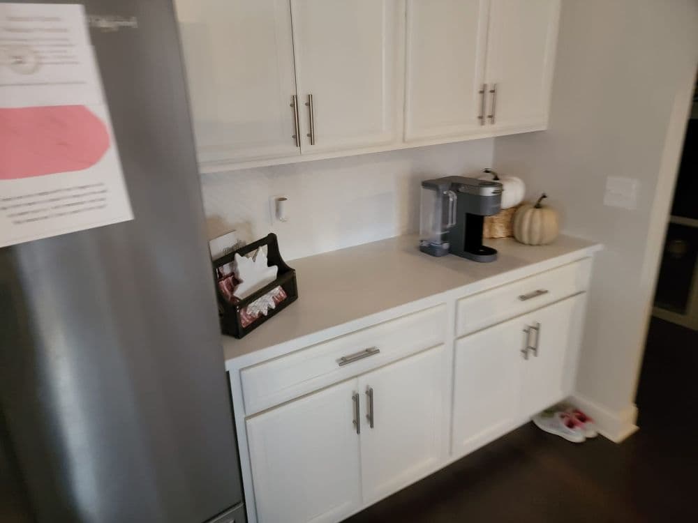 Modern kitchen corner with white cabinets, coffee maker, and decorative pumpkin.