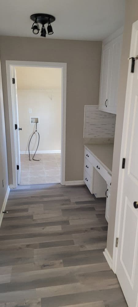 Modern kitchen interior with white cabinets, gray tile flooring, and natural light.