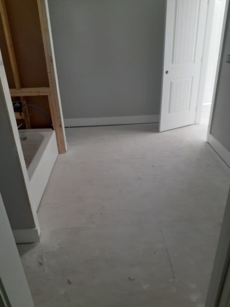 Empty room with unfinished flooring, gray walls, and open door to adjacent space.