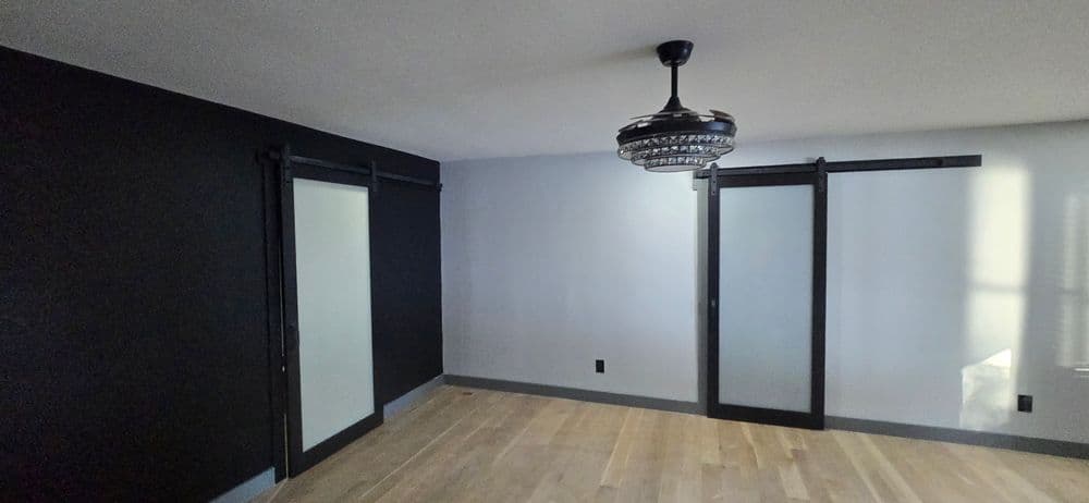Modern room interior featuring barn doors, a stylish chandelier, and hardwood flooring.