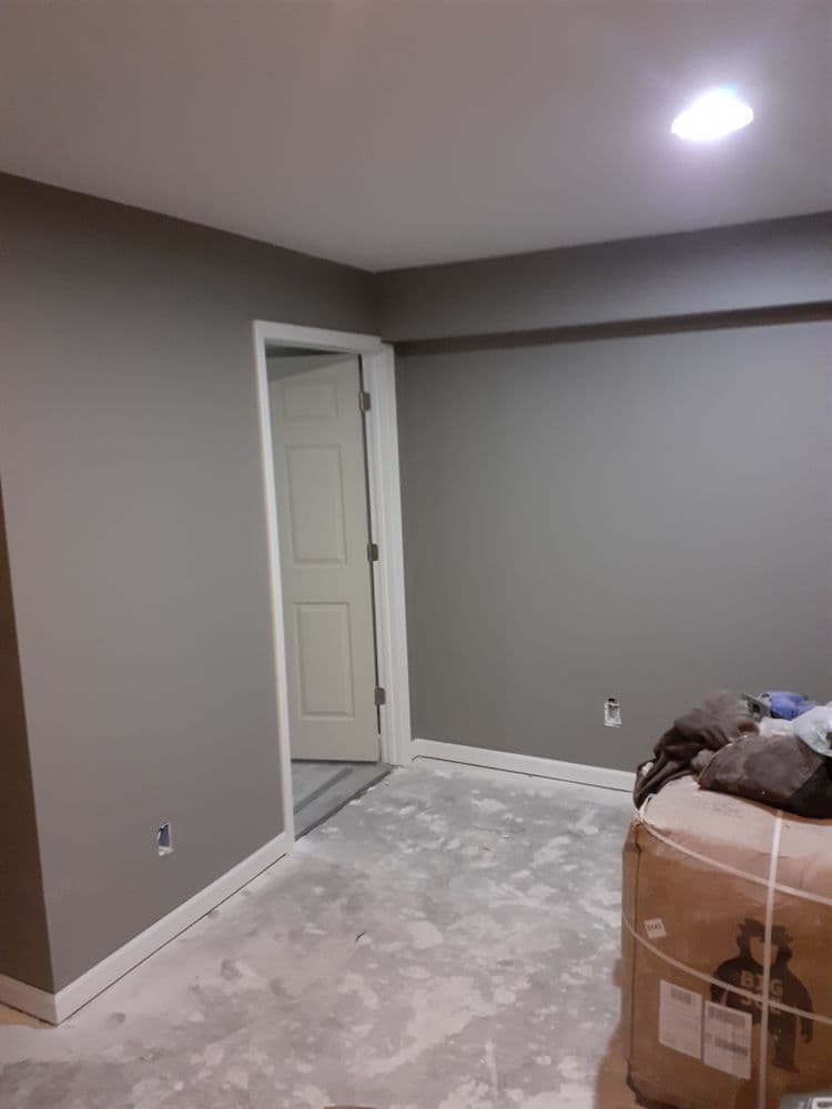 Interior of a newly renovated room with gray walls, an open door, and construction materials.