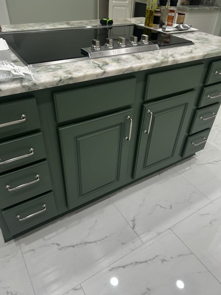 Green kitchen island with marble countertop and modern silver handles, in a stylish kitchen.