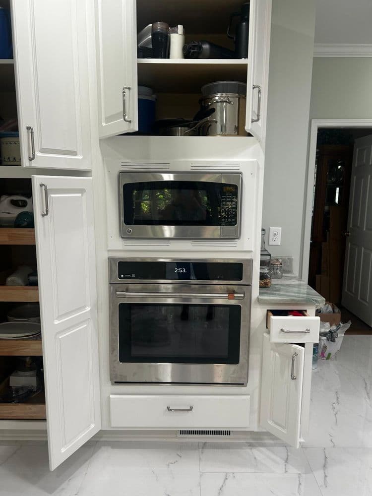 Modern kitchen with white cabinetry featuring built-in microwave and oven combination.