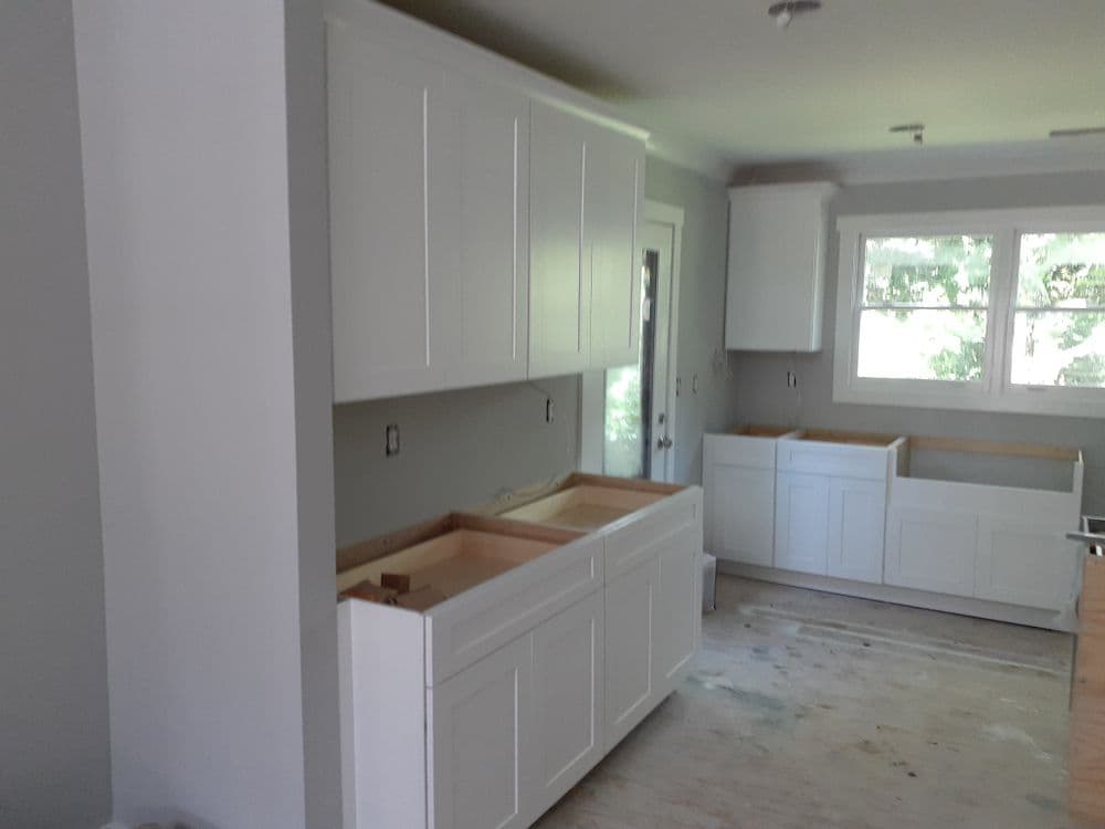 White kitchen cabinets installed in a modern home with natural light from a nearby window.
