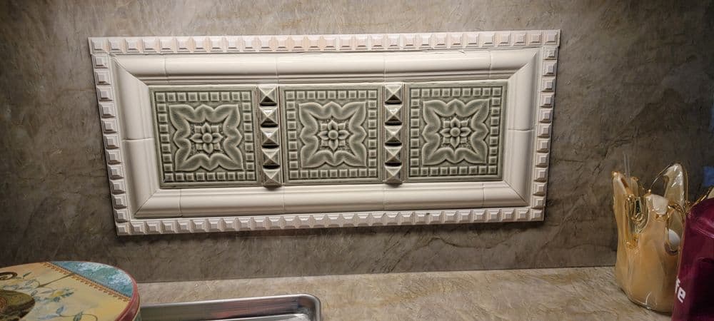 Decorative 3-panel tile backsplash with intricate floral patterns and a textured border.