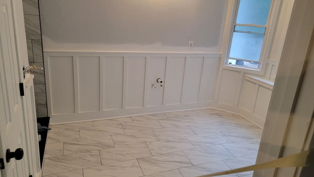 Spacious room with white wainscoting, gray walls, and marble-like tile flooring.