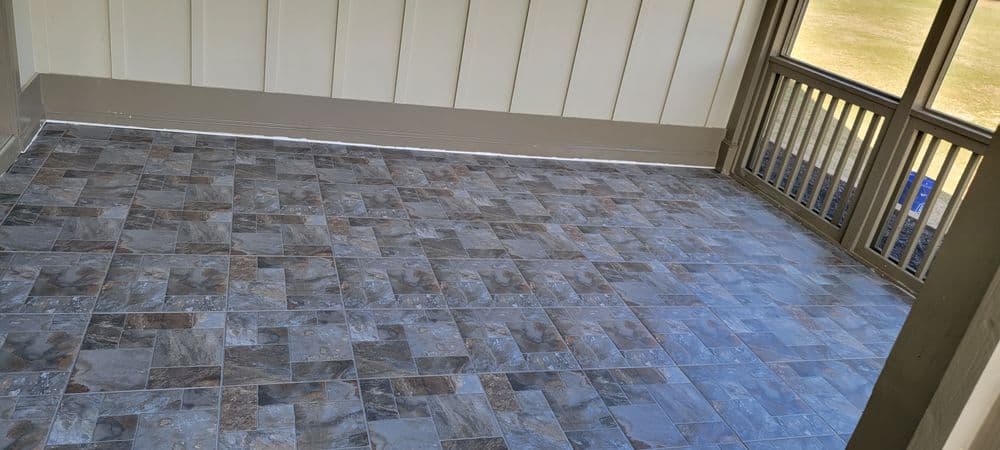 Modern gray tiled floor in a spacious sunroom with natural light and wooden railing.