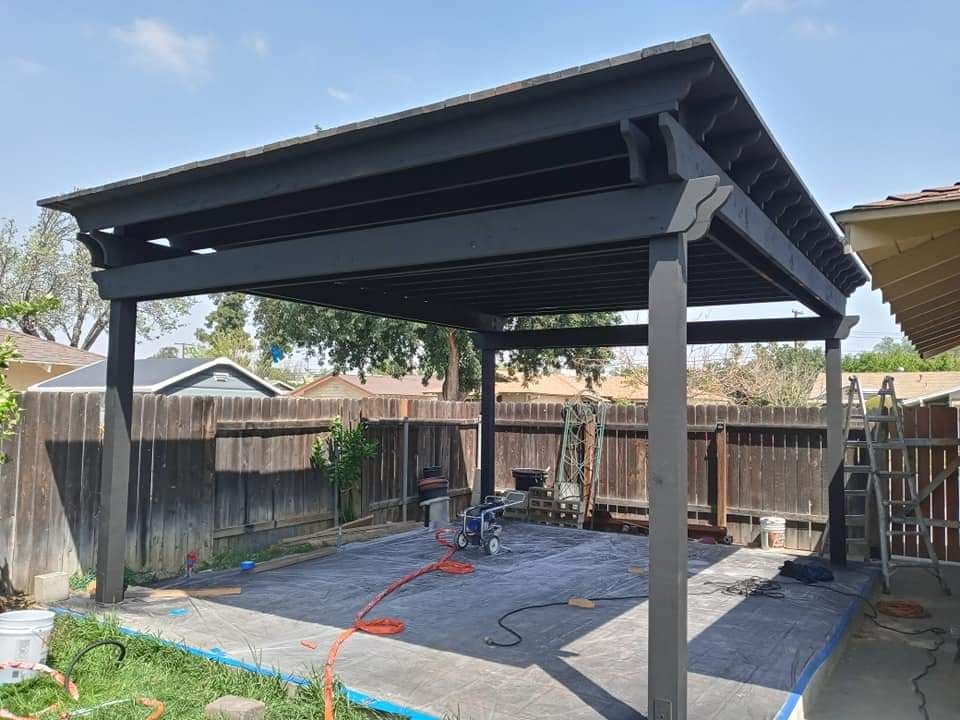 Black pergola structure installed in backyard with construction tools and materials visible.