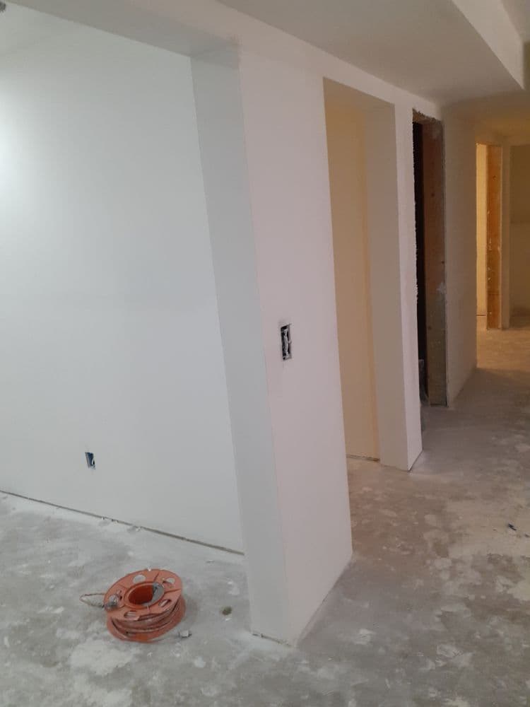 Interior construction site with unfinished walls and electrical outlet, featuring a spool of cable.
