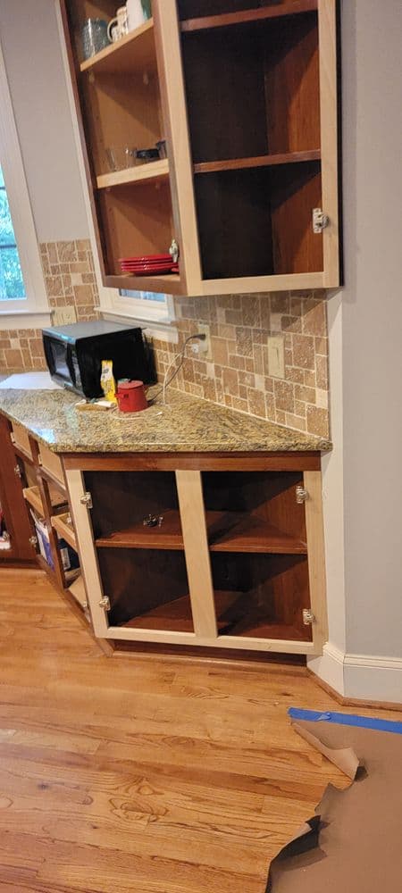 Modern kitchen corner cabinet with open shelves, granite countertop, and tiled backsplash.