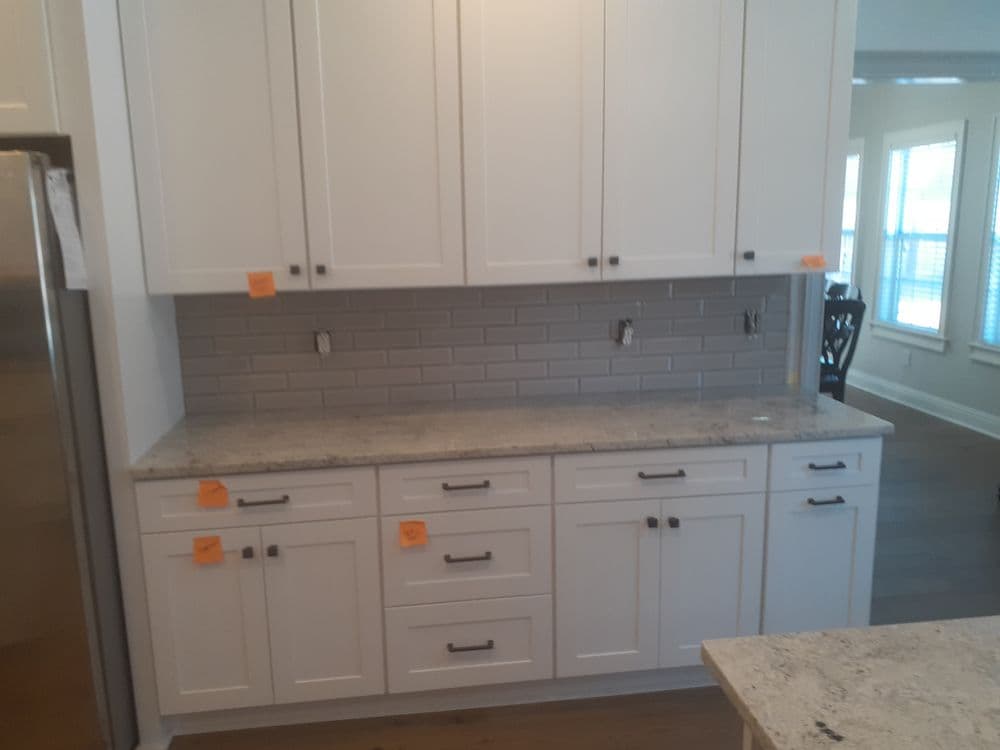 Modern kitchen with white cabinets, gray backsplash, and granite countertop.