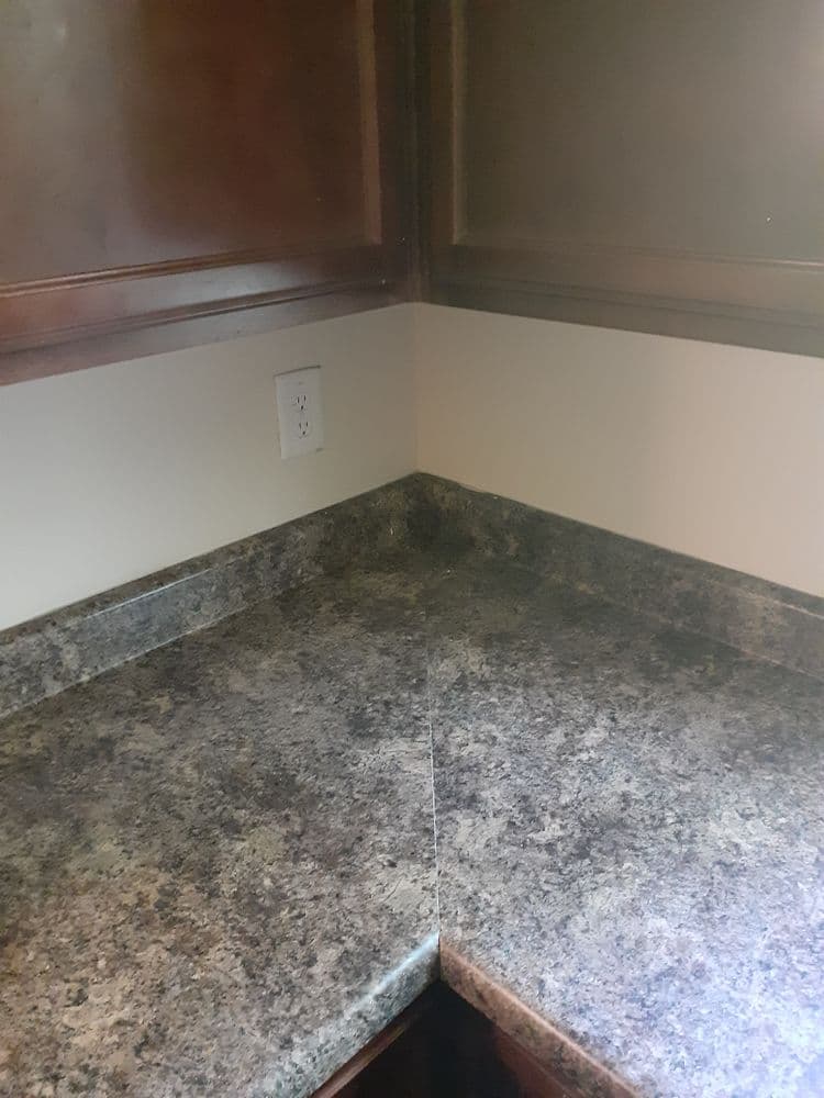 Corner kitchen countertop with dark granite surface and wooden cabinetry.