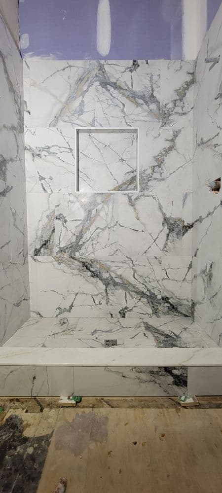 Modern shower design featuring elegant marble tiles with a niche, under construction.