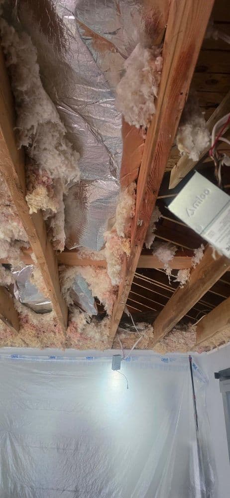 Exposed ceiling beams with insulation materials during home renovation project.